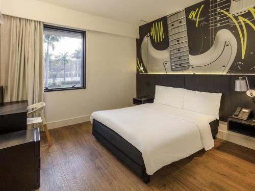 a hotel room with a bed and a guitar on the wall at ibis Styles Taubate in Taubaté