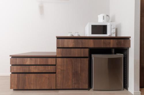 LANG HOTEL Kameido - Vacation STAY 79286v في طوكيو: ميكروويف موضوع فوق خزانة خشبية