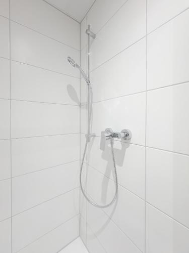 a shower with a hose in a white tiled bathroom at C&M Hotel in Hamburg