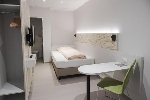 a small room with a bed and a desk and a table at C&M Hotel in Hamburg
