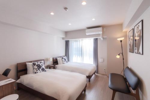ein Hotelzimmer mit zwei Betten und einem Schreibtisch in der Unterkunft LANG HOTEL Kameido - Vacation STAY 79478v in Tokio