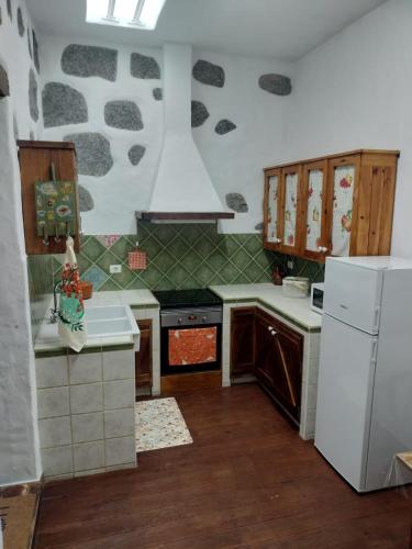 a kitchen with a stove and a white refrigerator at Casa Gloria, encanto canario entre montaña y mar in Arucas