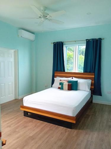 a bedroom with a bed with blue walls and a window at Serenity Seaview Suite in Anse La Raye