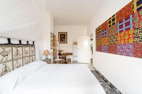 a bedroom with a white bed and colorful art on the walls at Camera con bagno privato e terrazzo a 10 minuti dalla Stazione Centrale - Oasis Bologna Centro in Bologna