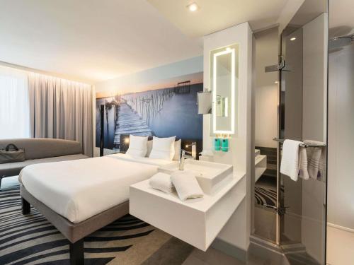 a hotel room with a bed and a sink at Novotel Paris Coeur d'Orly Airport in Orly
