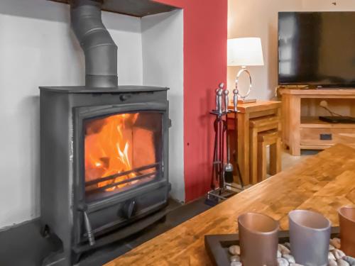 a wood stove in a room with a table at Fourwinds in Keswick