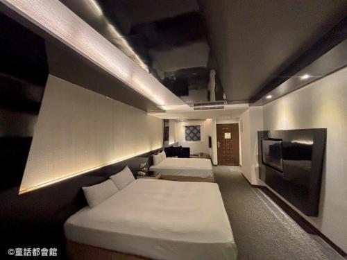 een kamer met 2 bedden en een televisie bij Fairy Tale City Motel in Hualien