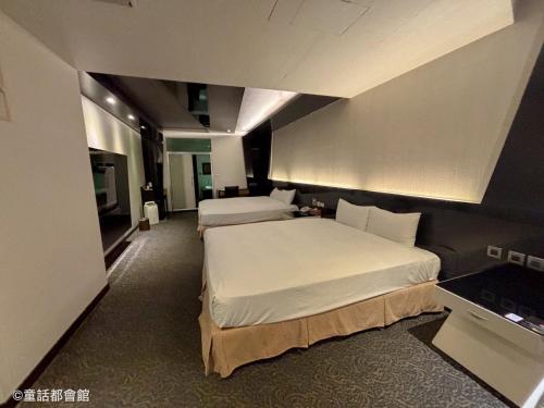 een slaapkamer met 2 bedden en een televisie bij Fairy Tale City Motel in Hualien