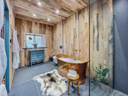 a bathroom with a wooden wall and a tub at Buttercup Cottage in Treborough