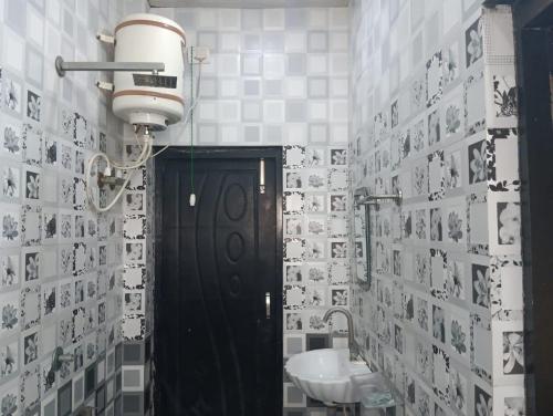 baño con puerta negra y lavamanos en Hotel Tirupati Lawn, en Lucknow