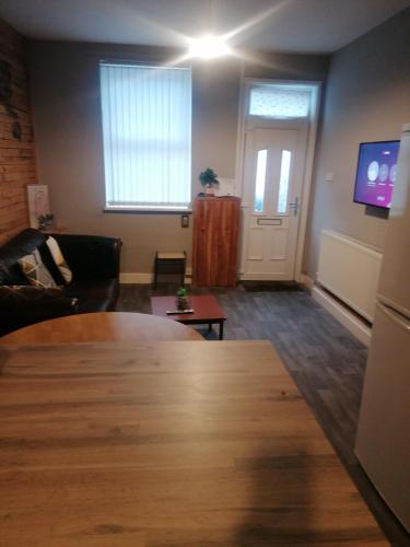 a living room with a table and a tv at Conway Home of Relaxations in Stoke on Trent