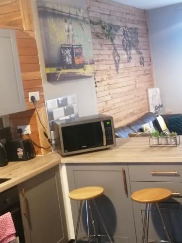 a kitchen with a counter with a microwave and stools at Conway Home of Relaxations in Stoke on Trent