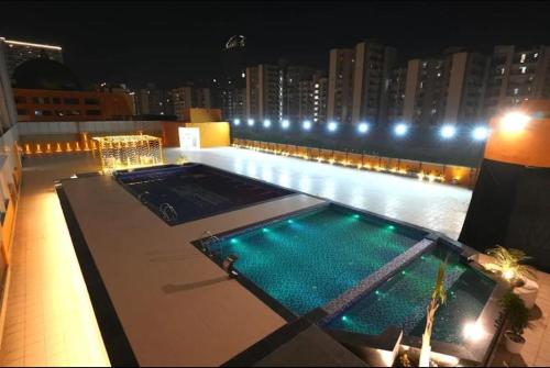 诺伊达Paris Style Luxe Apartment In The Heart Of Noida的夜晚的建筑物顶部的游泳池