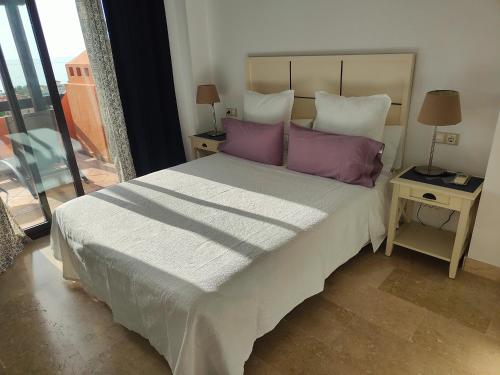 a bedroom with a large bed with purple pillows at Ático de lujo con vistas al mar in Estepona