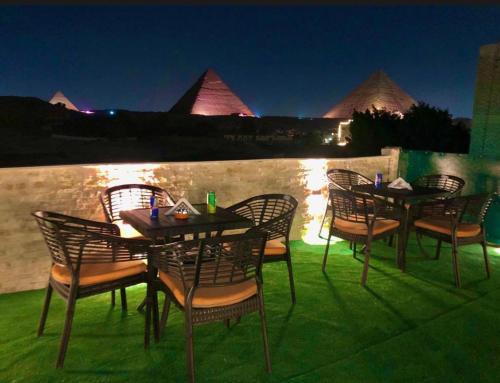 een groep tafels en stoelen op een patio 's nachts bij Lumora Pyramids InN in Caïro