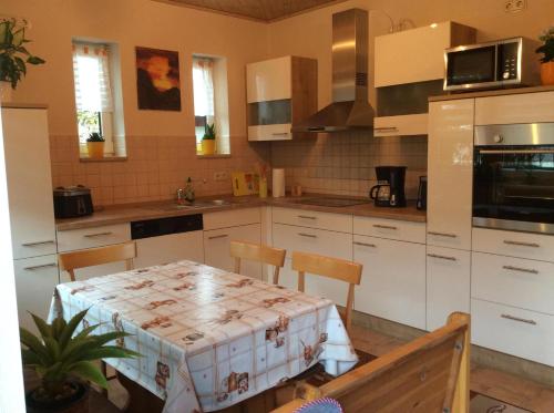 une cuisine avec des armoires blanches et une table avec des chaises dans l'établissement Ferienwohnung In Neustrelitz Mit Garten Und Grill, à Neustrelitz