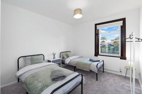deux lits dans une chambre blanche avec une fenêtre dans l'établissement Free Parking - Central - Sleeps 6 - 3 Bedrooms, à Tranent