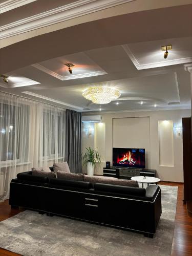 a living room with a large couch and a tv at 4х На берегу Иртыша in Pavlodar