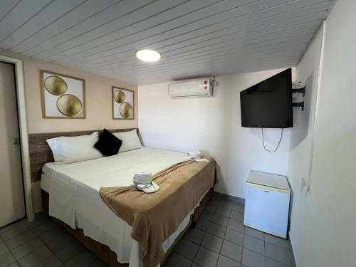 a small bedroom with a bed and a television at Pousada Villa Goyá in São José da Coroa Grande