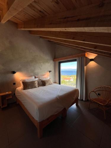 a bedroom with a large bed with a large window at Casa do Atalho in Santo Amaro