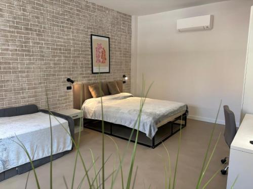 a bedroom with two beds and a brick wall at Typic loft Alghero in Alghero