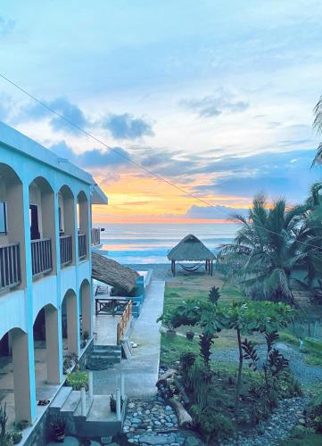 ein Gebäude am Strand mit einem Sonnenuntergang im Hintergrund in der Unterkunft Brisa Bliss in San Juan de Alima