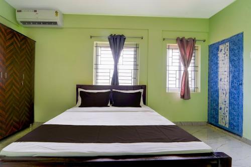 Cama en habitación con paredes y ventanas verdes en Collection O MKU Madurai Formerly Mpl Elite, en Samayanallūr