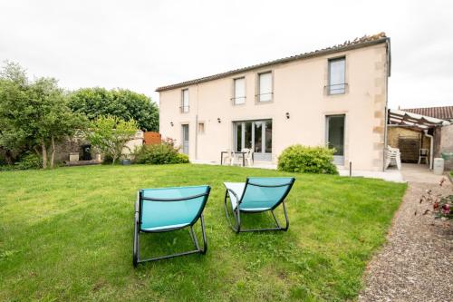 zwei Stühle im Gras vor einem Haus in der Unterkunft Maison du Château, spacieuse et charmante près du PuyDuFou in Mortagne-sur-Sèvre