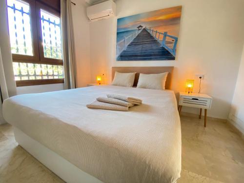 a bedroom with a large white bed with towels on it at Casa Kessing in Orihuela Costa