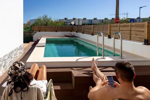 two people sitting in chairs next to a swimming pool at Outsite Sagres - Work, Connect, Explore in Sagres