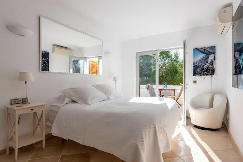 a white bedroom with a white bed and a chair at Beautiful Sea View Villa Minerva in Sant Josep