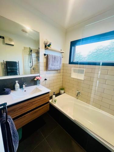 a bathroom with a tub and a sink and a mirror at Decked Out with a View in Motueka