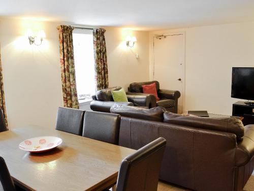 ein Wohnzimmer mit Sofa und Tisch in der Unterkunft Courtyard Cottage in Smailholm