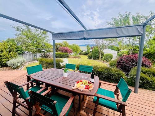 uma mesa de madeira e cadeiras em um deck em Decked Out with a View em Motueka