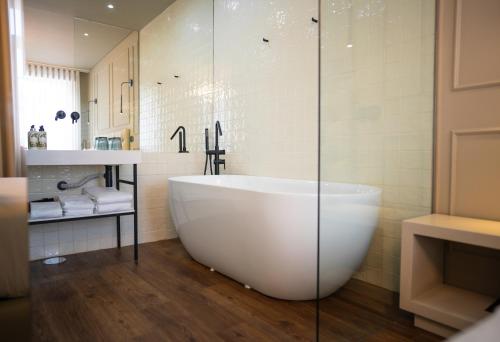 サント・ティルソにあるSanto Thyrso Hotelのバスルーム(大型バスタブ、ガラス張りのシャワー付)