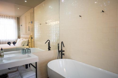 a white bathroom with a tub and a sink at Santo Thyrso Hotel in Santo Tirso
