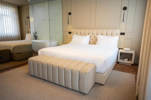 a bedroom with a large white bed and a stool at Santo Thyrso Hotel in Santo Tirso