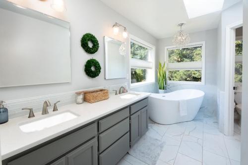 ein Badezimmer mit zwei Waschbecken, einer Badewanne und Fenstern in der Unterkunft Sopra Bella- 4 bedroom home in Corvallis