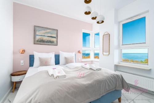 ein weißes Schlafzimmer mit einem großen weißen Bett mit Fenstern in der Unterkunft Your Holidays Aquamarina Onyx 98 in Misdroy