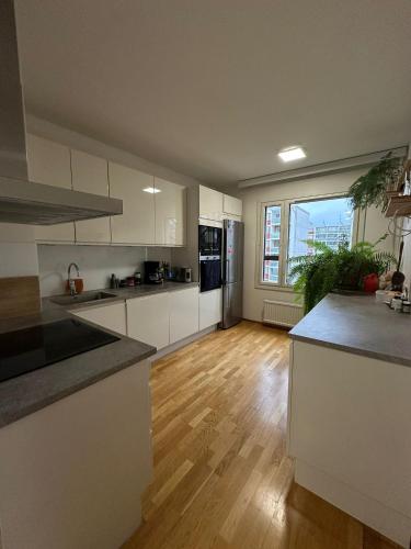 a kitchen with white cabinets and a wooden floor at 2 room apartment in Pasila in Helsinki