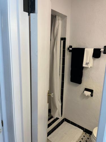 a bathroom with a shower with black and white towels at Boots Court Motel in Carthage