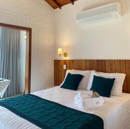 a bedroom with a large white bed with blue pillows at Chalé Colibri Verde in Santa Teresa