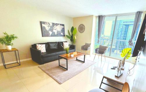a living room with a black couch and a table at Bright & Modern Condo in Brickell w Pool Access in Miami