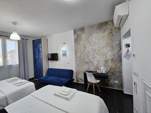 a hotel room with two beds and a blue couch at Affittacamere Casa Marconi in Comacchio
