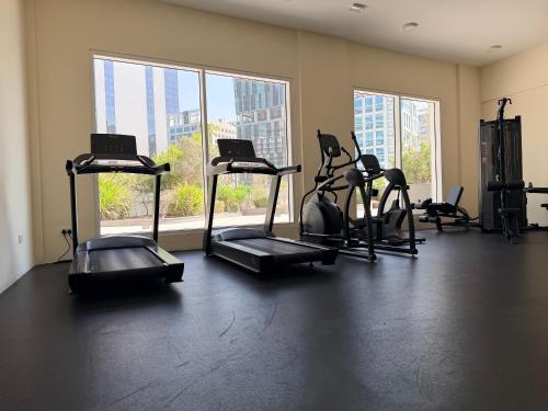 - une salle de sport avec plusieurs tapis de course dans une pièce dotée de fenêtres dans l'établissement Convenient studio in the centre of Dubai, à Dubaï