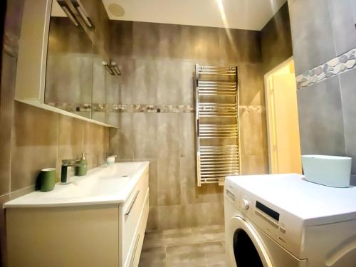 Arty chic flat between Arc de Triomphe & Eiffel Tower في باريس: حمام مزود بحوض غسيل وغسالة ملابس