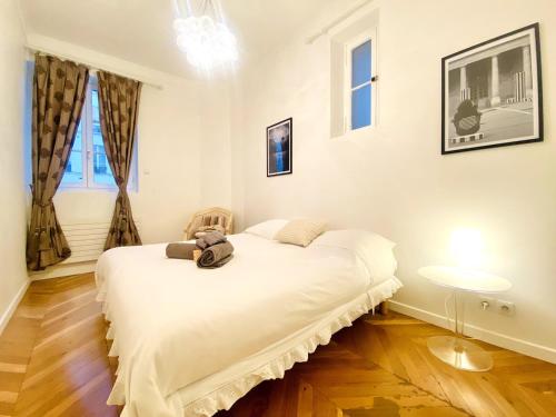 Arty chic flat between Arc de Triomphe & Eiffel Tower في باريس: غرفة نوم بها سرير أبيض عليه دمية محشوة