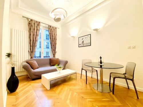 Arty chic flat between Arc de Triomphe & Eiffel Tower في باريس: غرفة معيشة بها طاولة وأريكة