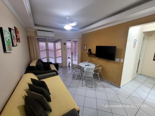 ein Wohnzimmer mit einer Couch und einem Tisch und einem Fernseher in der Unterkunft Casa em Caraguá, uma quadra da praia com ar in Caraguatatuba