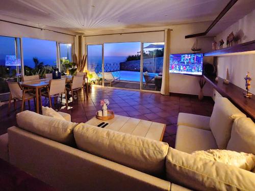 a living room with a large couch and a television at Villa Ocean Wave Calheta - Heated Pool & Stunning Ocean View in Calheta